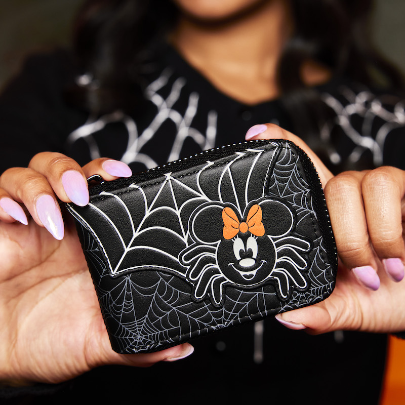 Woman holding the Minnie Mouse Spider Accordion Wallet out toward the camera, featuring a spiderweb and a spider version of Minnie Mouse on the front